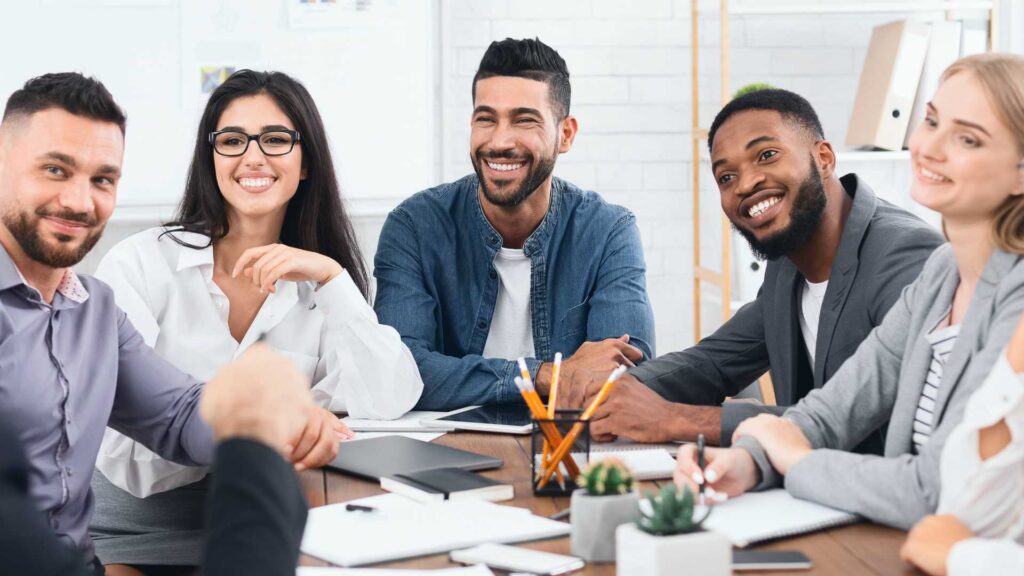 Happy business team listening to director at group meeting in office