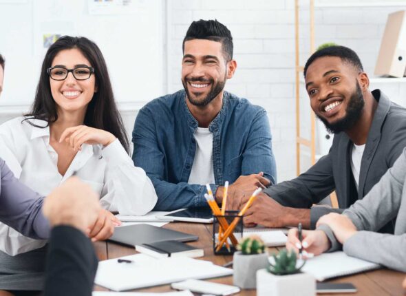 Happy business team listening to director at group meeting in office